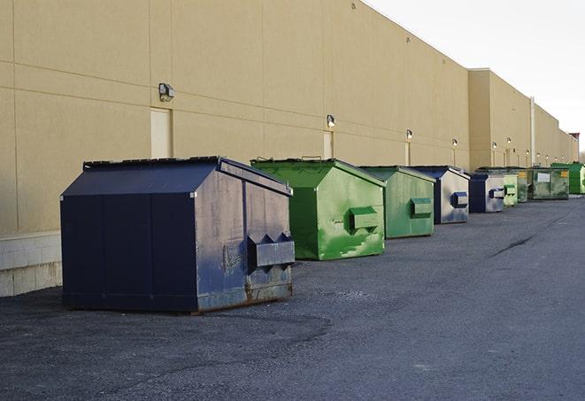 a waste management truck unloading into a construction dumpster in Albertville